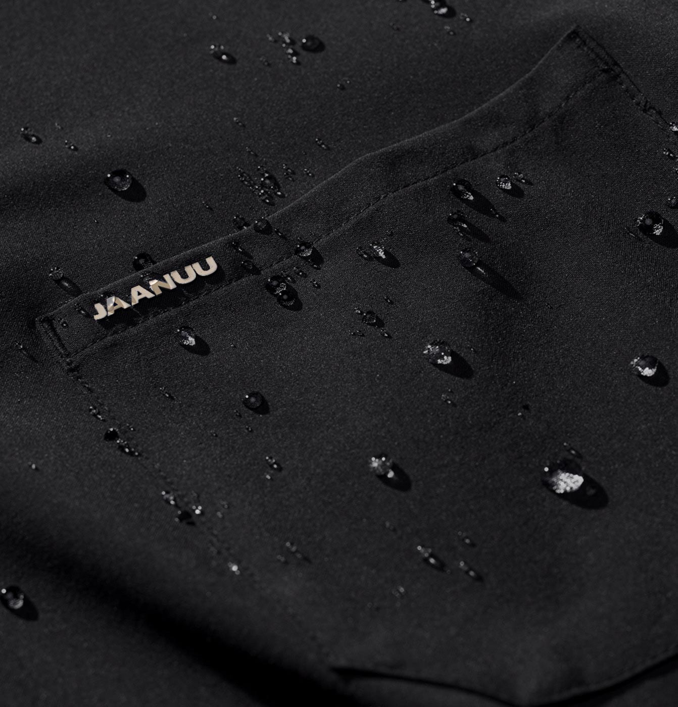 Closeup image of Jaanuu scrub fabric with PFC-free water repellent treatment. Water droplets are sitting on the scrub with out soaking through.