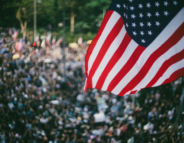 A crowd of people with the American flag in the foreground.