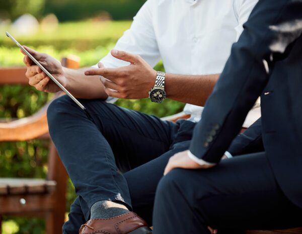 Two men sitting looking at a tablet.