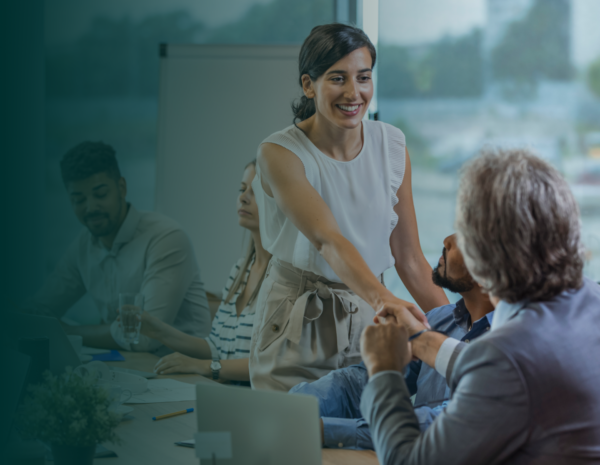 A young woman and older man shaking hands in a professional setting.