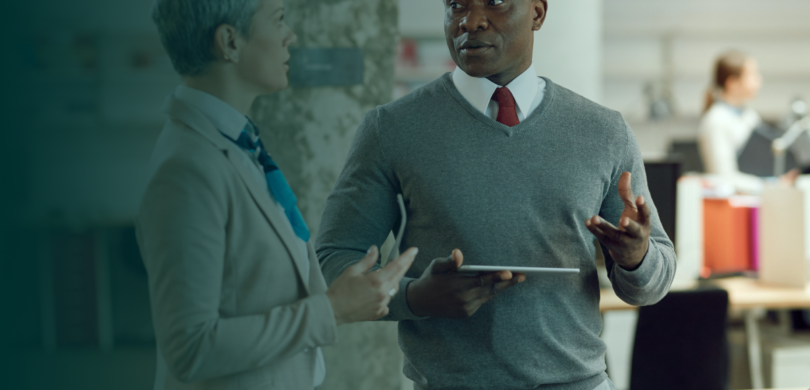 A man and a woman stand in an office setting.